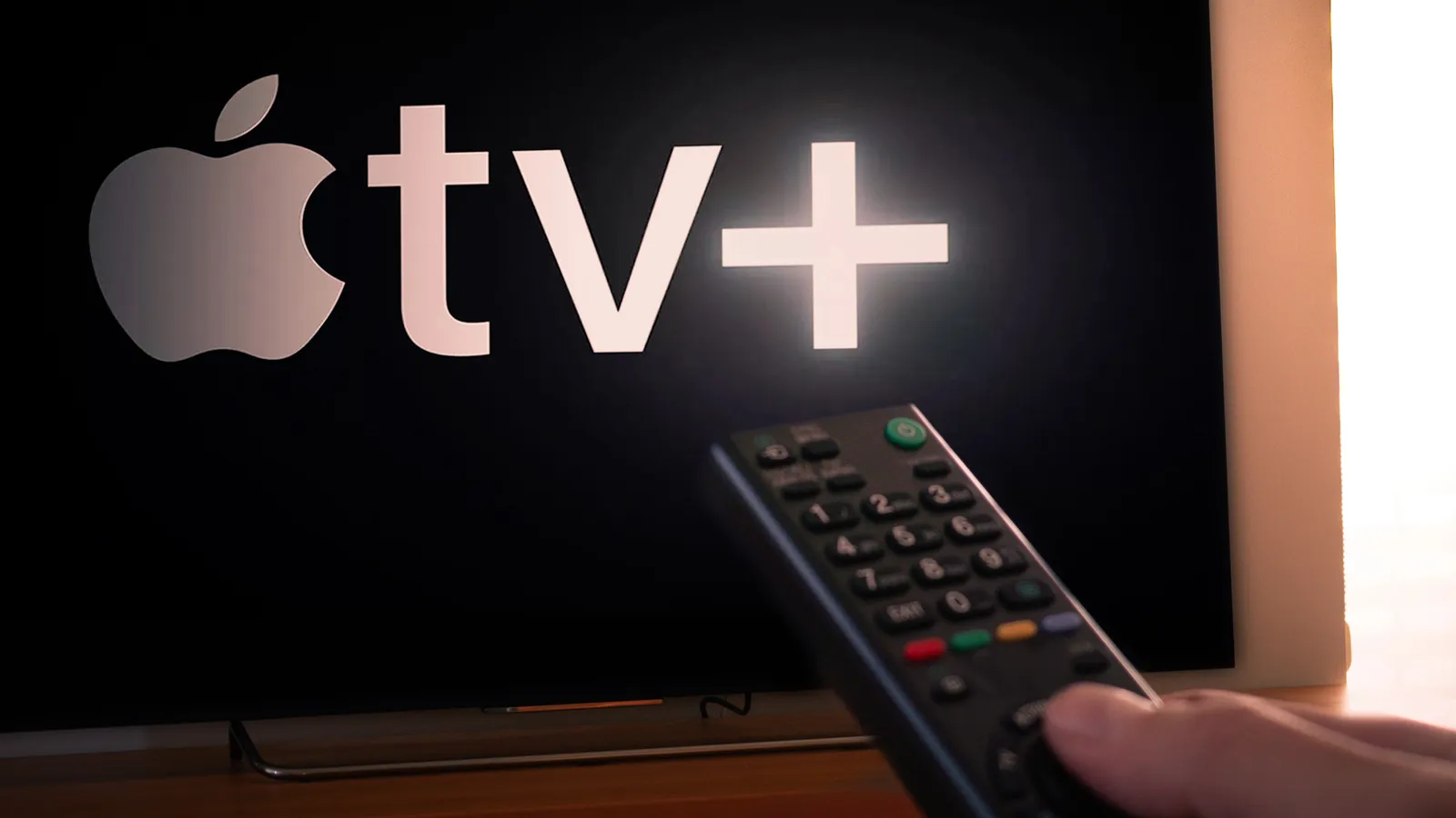 Man holding tv remote pointing towards Apple TV screen