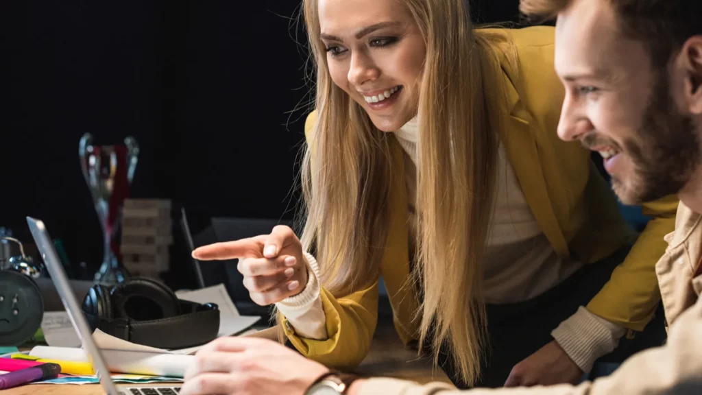 smiling female and male it specialists using laptop in office