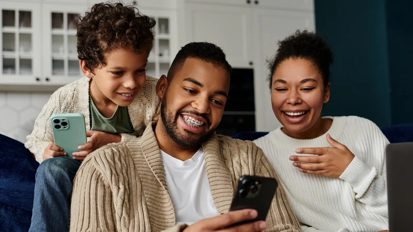 African-American family engrossed in a cell phone while seated