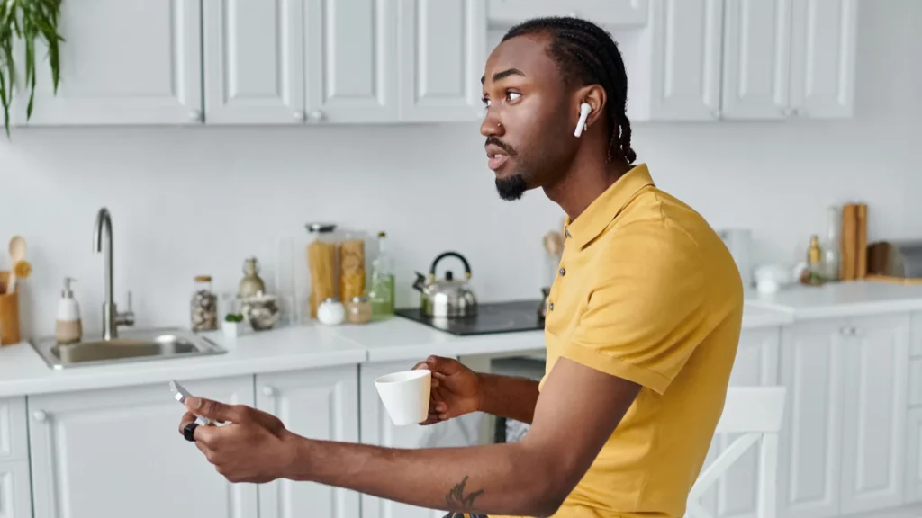 young man with airpods sipping coffee while working on his