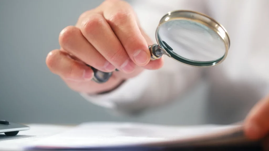 Businessman reading documents with magnifying glass
