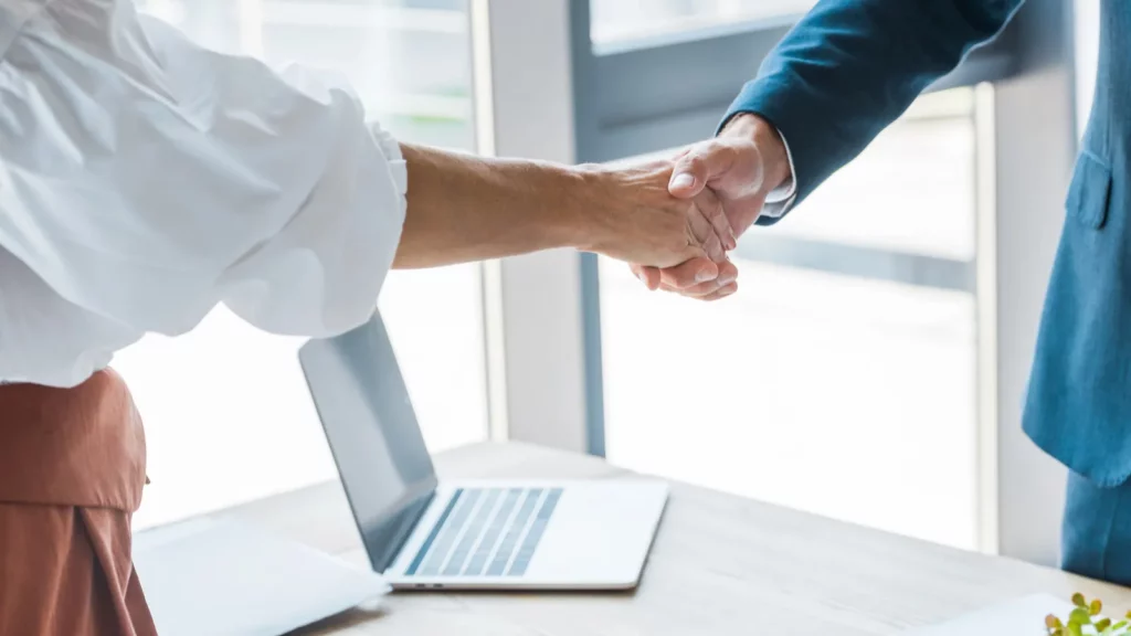 Cropped view of employee and recruiter shaking hands in office after being hired