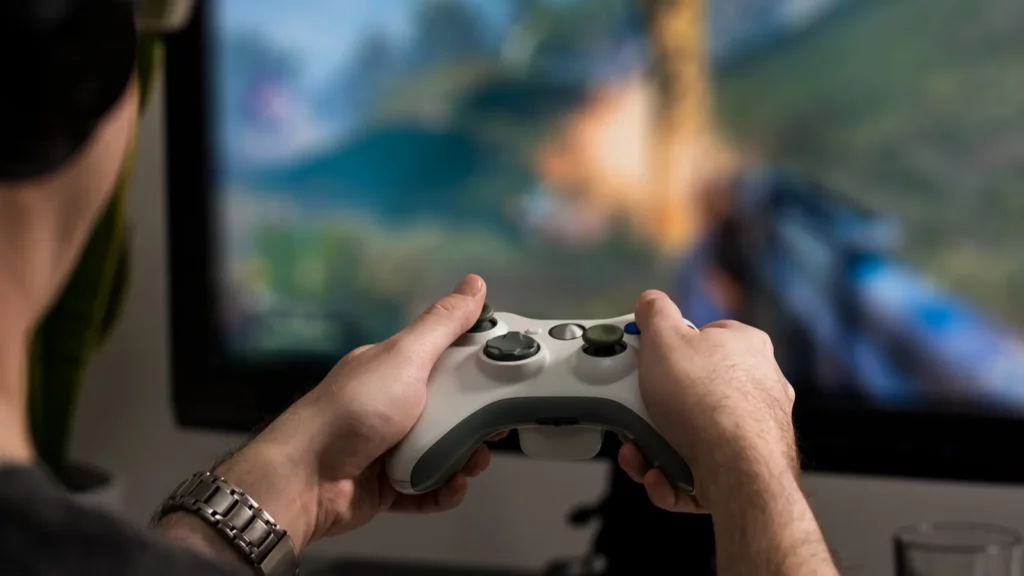 man playing on console with joystick and wearing headphones